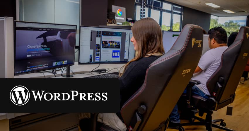 female developer sitting at a triple-monitor workstation with an ocular charging website showing charging ahead visible on screen, with a colour wheel app and design files open on secondary displays, in the open-plan norwest office with the wordpress logo overlaid.