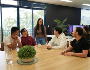 Click Click Media team members chat and laugh around a meeting table in the agency's bright Norwest office.