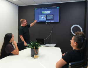 A Click Click Media team member presents the agency's website on a wall screen to colleagues in the boardroom.