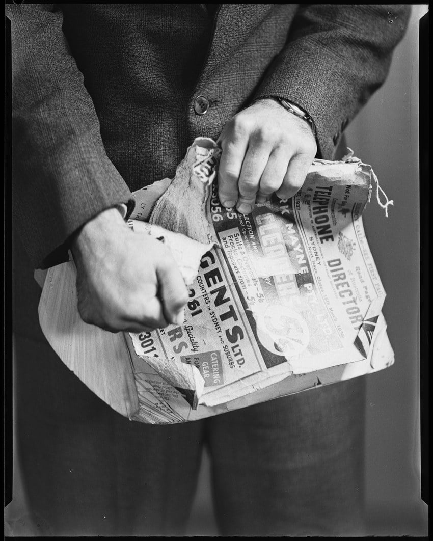 a man tears a battered sydney telephone directory in half, photographed 2 june 1938.